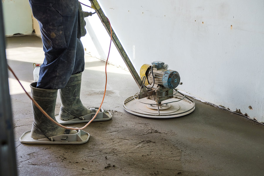 man refinishing, smoothening the concrete floor
